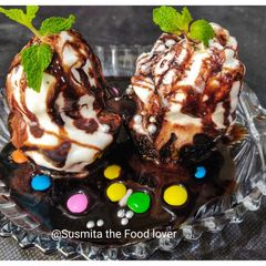 A picture of Chocolate cupcakes loaded with ice cream and chocolate sauce.