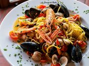Una foto di pasta con gamberoni e vino