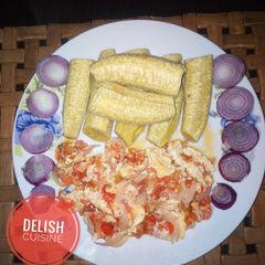 A picture of Boiled unripe plantain and egg sauce garnished with onions.