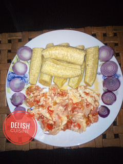A picture of Boiled unripe plantain and egg sauce garnished with onions.