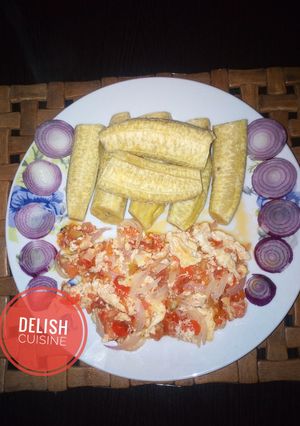 A picture of Boiled unripe plantain and egg sauce garnished with onions.