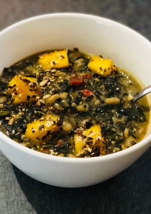 A picture of White Bean and Swiss Chard Egusi Soup with seed coated Polenta bites.