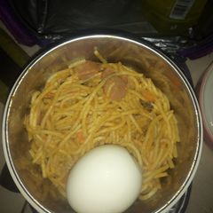 A picture of Jollof Spaghetti boiled egg and sausage.