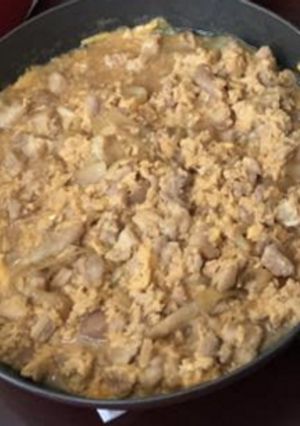 A picture of Bowl of rice topped with chicken and eggs.