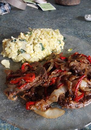 Una foto de Higadito salteado con cebolla y morrón acompañado con un revuelto de verduras y arroz