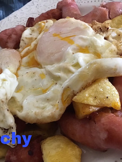 Una foto de Huevos sobre fritada de salchichas y patatas