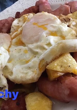 Una foto de Huevos sobre fritada de salchichas y patatas