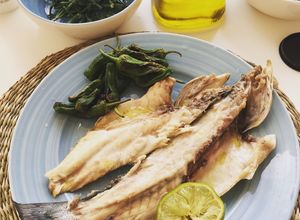 Una foto de Lubina a la plancha con pimientos de Padrón y salicornia