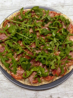 Una foto de Pizza de rúcula, jamón, tomate y queso