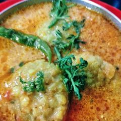 A picture of Besan tikki in Tomato and Curd gravy.