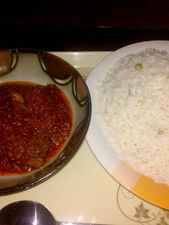 A picture of White rice with green peas and stew.