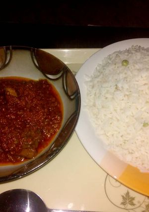 A picture of White rice with green peas and stew.