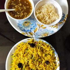 A picture of Veg biryani mounchrian soup and salad with fried Maggi.