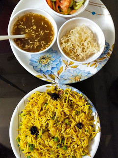 A picture of Veg biryani mounchrian soup and salad with fried Maggi.