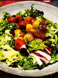 Una foto de Ensalada templada: tomatitos confitados y caramelizados con albahaca fresca y concentrado de Módena
