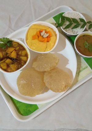 A picture of Gujarati lunch (rasadar aloo sabji, amrakhand, puri, dal, rice).