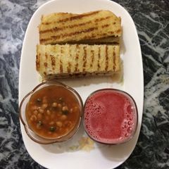 A picture of Baked beans with homemade garlic bread and fresh watermelon juice.
