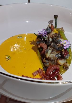 Una foto de Chile de agua relleno de huitlacoche con espejo de crema de pimiento y gusanito de maguey