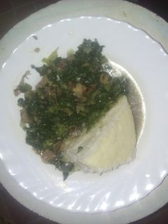 A picture of Ugali served with fried spinach  mixed with beef meat.