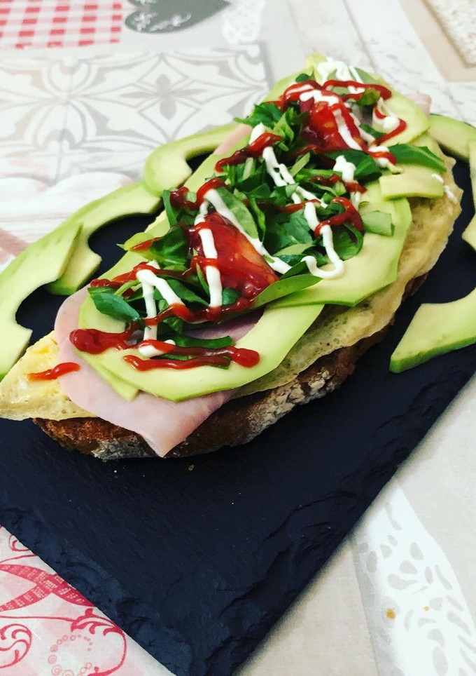Una foto de Tostada de tortilla y jamón york, aguacate y canónigos