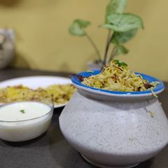 A picture of Veg dum biryani with smoked curd.