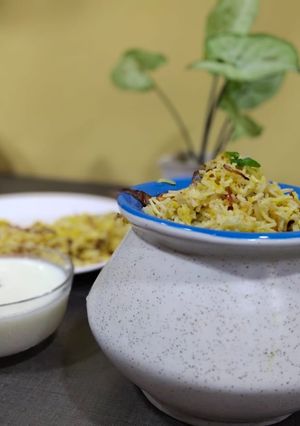A picture of Veg dum biryani with smoked curd.