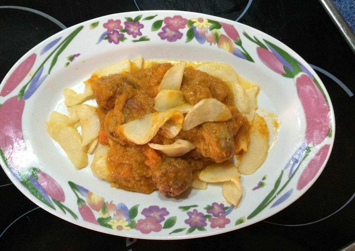Albóndigas de ternera en salsa sobre una cama de patatas fritas redondas