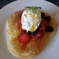 A picture of Pancakes with whipped cream and berries.