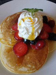 A picture of Pancakes with whipped cream and berries.