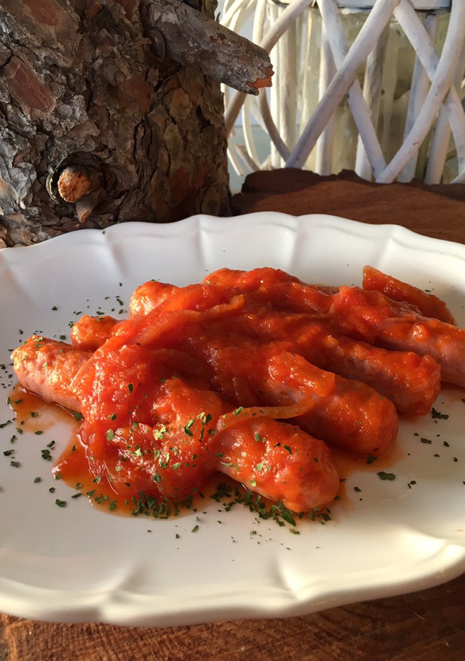 Una foto de Longanizas (o salchichas) encebolladas con tomate