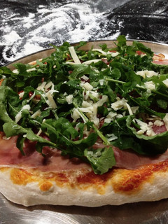 Foto de Pizza com rúcula, presunto cru, tomate cereja e parmesão