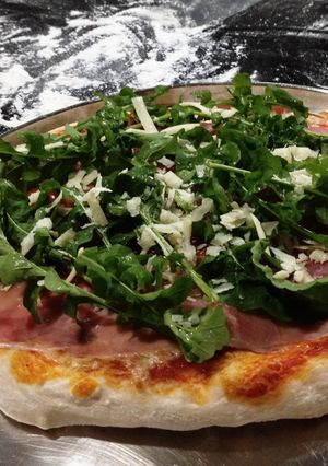 Foto de Pizza com rúcula, presunto cru, tomate cereja e parmesão