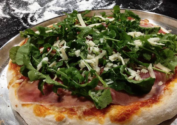 Pizza com rúcula, presunto cru, tomate cereja e parmesão