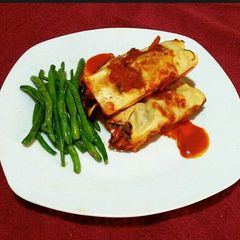 A picture of Enchiladas and steamed glazed runner beans.