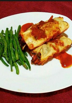A picture of Enchiladas and steamed glazed runner beans.
