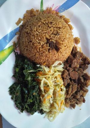 A picture of Pilau served with spinach, wet fried beef and steamed cabbage.