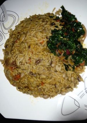 A picture of Palm Oil Rice and Beans Jellof Garnished with vegetable.