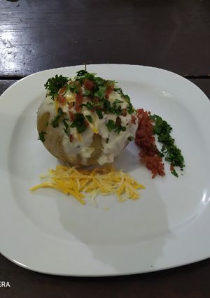 Una foto de Papa horneada con tocino y crema