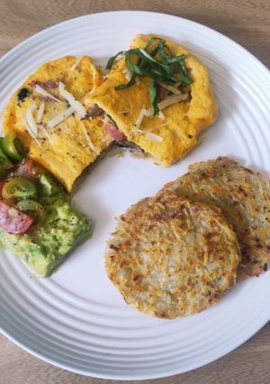 Una foto de Omelette relleno, hashbrown y crema de aguacate