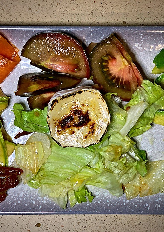 Una foto de Ensalada de tomates, aguacate, verduras encurtidas y rulo de cabra tostado