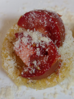A picture of Polenta topped with Parmesan and tomato.