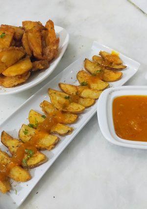 A picture of Crispy potato wedges with spicy mango sauce.