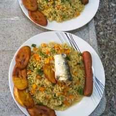 A picture of Indomine with fried plantain,sausage,carrots and spring onion.