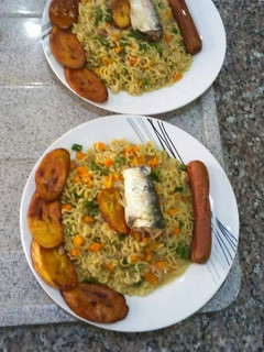 A picture of Indomine with fried plantain,sausage,carrots and spring onion.