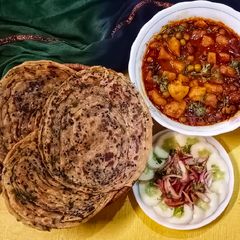 A picture of Masala laccha paratha with aloo matar in tomato gravy.
