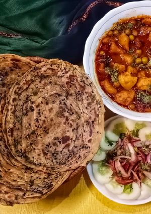 A picture of Masala laccha paratha with aloo matar in tomato gravy.