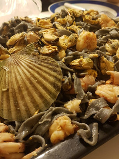 Una foto de Fideos negros con salsa de langostinos mejillones y vieiras