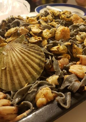 Una foto de Fideos negros con salsa de langostinos mejillones y vieiras