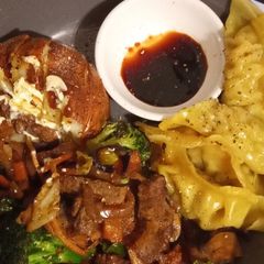 A picture of Jacket potato with beef stir fry and gyoza chicken dumplings.