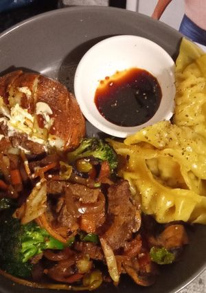 A picture of Jacket potato with beef stir fry and gyoza chicken dumplings.